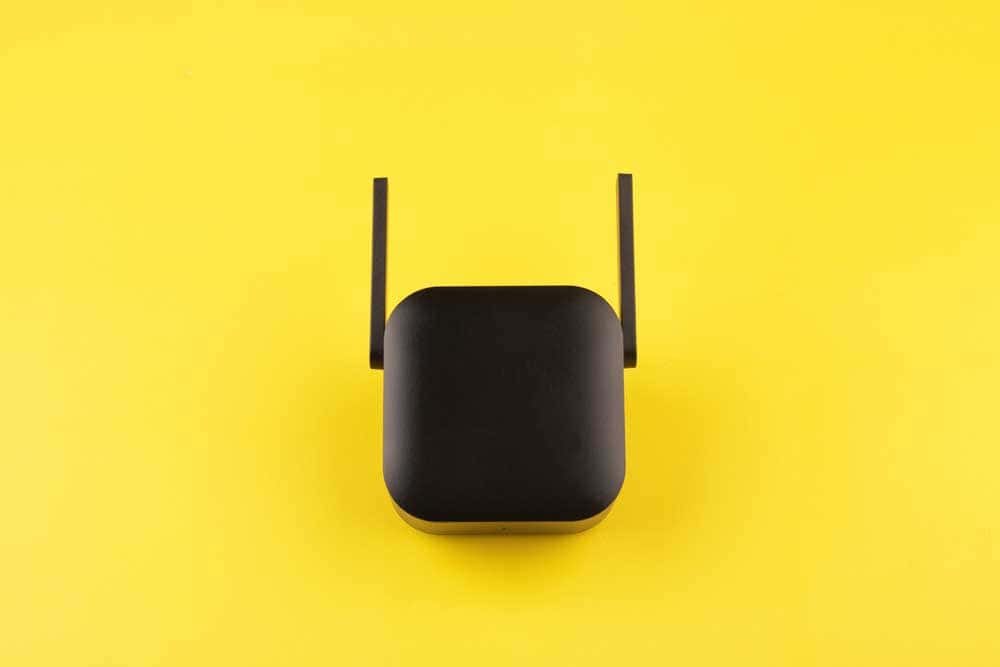 Black WiFi signal booster on a yellow background