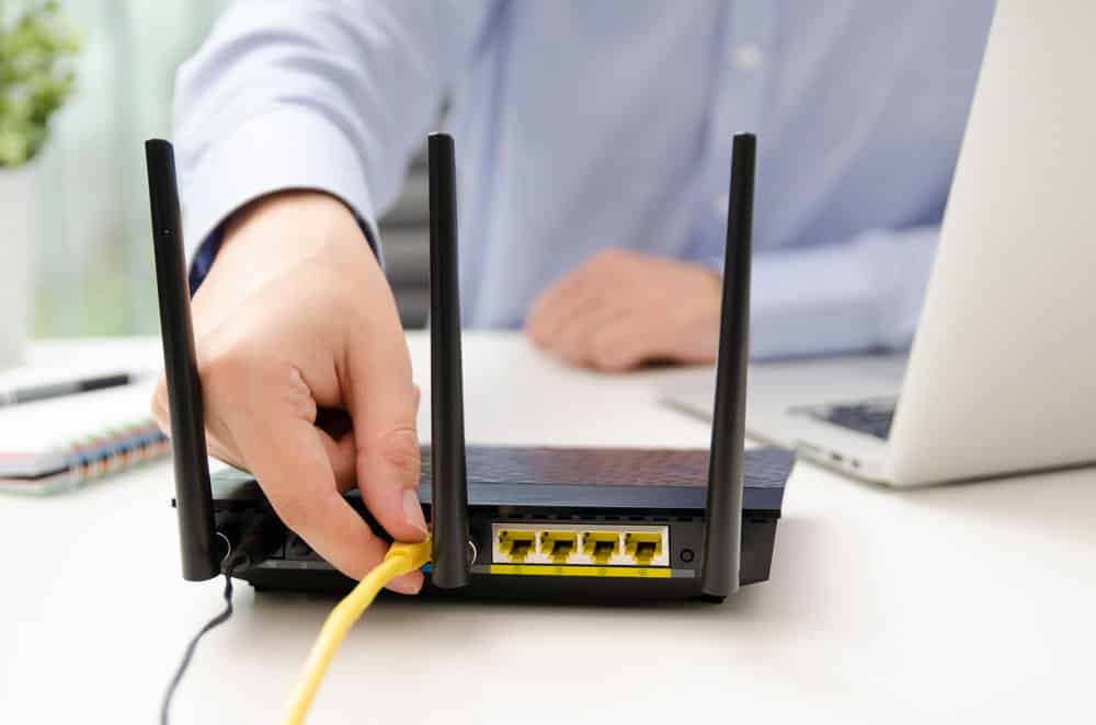 A man plugging Ethernet cable into a router