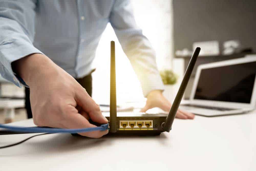 A man connecting Ethernet cable to a WiFi router